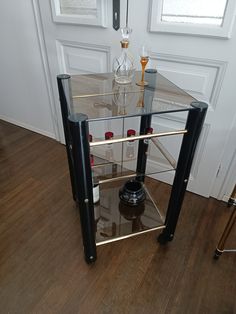 a glass and metal side table with bottles on it