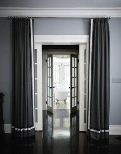 an open door leading to a bathroom with black and white curtains