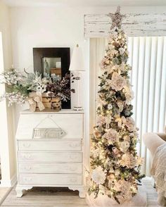 a white christmas tree sitting next to a dresser