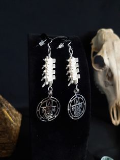 Here is a Gorgeous Pair of Sigil of Astaroth Earrings! They Were Made With Real Large Rattlesnake Vertebrae! The Hooks, Pendants and Jump Rings are All Stainless Steel. They Are Around 4 Inches long. All Items Ship Within 1-3 Days via USPS First Class Service,  With Some Upgrades Available Also. Shipping on These Will be 5.00. Additional Items are Free! International Shipping Will Be 20.00, And All Additional Items Are FREE! International Shipping May Take 2 - 6 Weeks to Deliver. I Always Love to Accommodate Custom Orders! If you Have Something in Mind, Please Message me. Have a Drawing or a Photo of Your Inspiration and Send it to Me! And Also, Please Send Me Your Preferred Budget for Your Piece, To Make Sure You are Not Overcharged. I DO NOT Carry Human Bones or Any Sort of Illegal Items Handmade Gothic Plug Earrings As Gift, Gothic White Dangle Jewelry, White Gothic Dangle Jewelry, Handmade Gothic Sterling Silver Earrings, Handmade Gothic Drop Earrings, Gothic Handmade Drop Earrings, Handmade Gothic White Jewelry, Handmade White Gothic Earrings, White Gothic Handmade Earrings