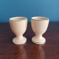 two white cups sitting on top of a wooden table