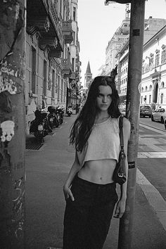 a woman standing next to a pole on a city street