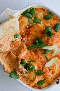 a casserole dish with meat, cheese and vegetables in it on a white surface