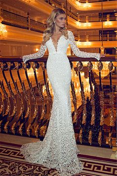 a woman in a long white dress standing on a balcony with chandelier lights