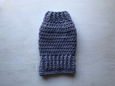 a crocheted blue and gray knitted hat laying on top of a wooden table