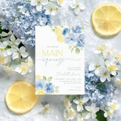 the wedding stationery is surrounded by lemons, blue flowers and white hydrangeas