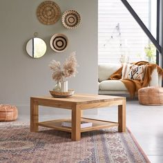 a living room with a coffee table, rug and wall hangings on the walls