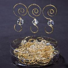 a glass bowl filled with lots of gold colored metal wire and some crystal beads hanging from it's sides