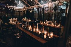 a long table with many lit candles on it in a room filled with chairs and tables