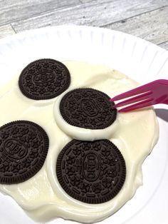 four oreo cookies sitting on top of a white plate next to two red straws