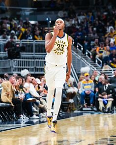 a basketball player walking on the court with his hand up to his mouth and people in the stands watching