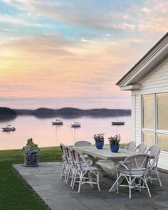 a table and chairs on a patio overlooking the water with boats in the lake behind it