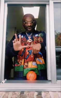 a man standing behind a window with his hands in the air while holding a basketball