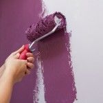 a person using a paint roller to paint a wall with purple paint and white trim