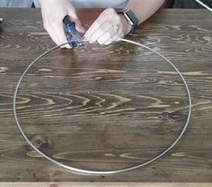 a woman is working on a metal object with scissors and wire around it, while another person looks at the camera in the background