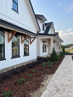 a house with white siding and black trim on the windows, along side a brick walkway