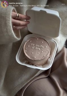 a woman is holding a cake in a plastic container with writing on the frosting