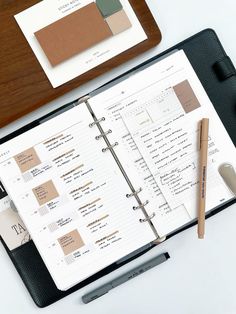 an open planner and pen sitting on top of a desk