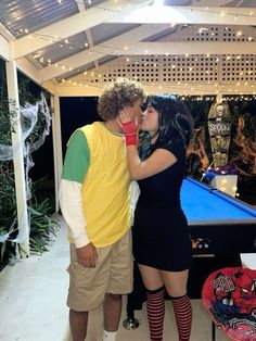 a man and woman kissing in front of a pool table