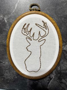 an embroidered deer's head is shown on a wooden hoop hanging from the wall