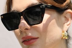 a close up of a person wearing sunglasses and a necklace with gold accents on it