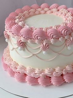 a large pink and white cake on top of a white platter with icing