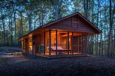 a small wooden cabin in the woods at night