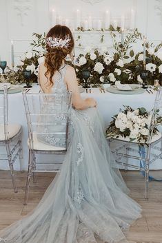 a woman sitting at a table wearing a dress with flowers on it and a tiara over her head