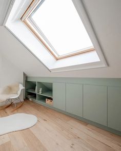 an attic bedroom with skylight and storage units on the wall, along with hardwood flooring