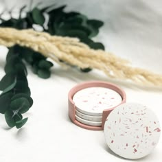 three round coasters sitting on top of each other next to some plants and leaves