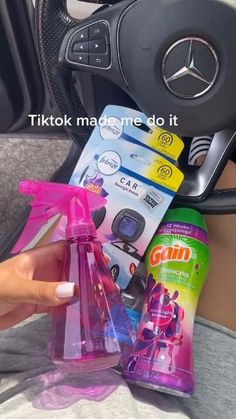 a woman is holding her hand over the steering wheel of a car with various cleaning products on it