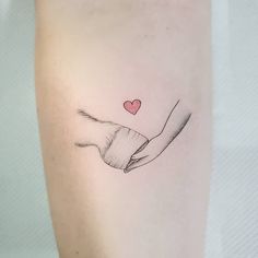 a woman's arm with a red heart on it and her hand holding something