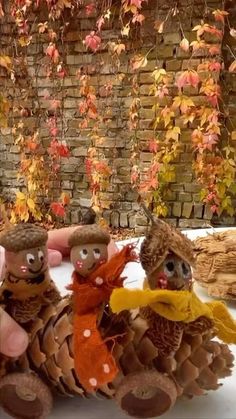 three stuffed animals sitting on top of a pile of pine cones