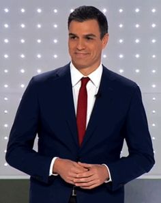 a man in a suit and tie is standing with his hands on his hips while looking at the camera