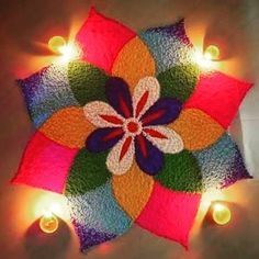 a colorful flower is lit up with candles