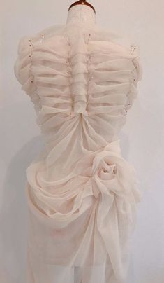 a mannequin wearing a white dress with ruffles on it's back