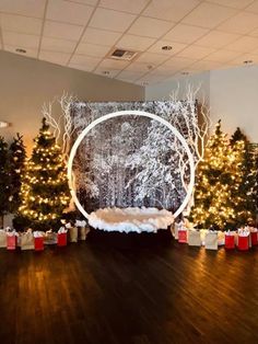 a room with christmas trees and presents on the floor in front of a large screen