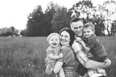 a man and woman holding two children in a field