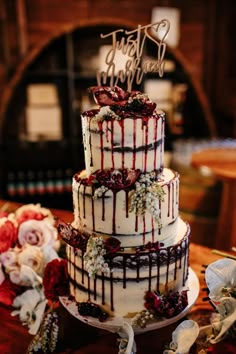 a three tiered wedding cake with red and white icing on top, sitting on a table