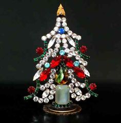 a small christmas tree with red, green and blue decorations on it's base