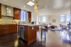 an open kitchen and living room area with hardwood floors, high ceilings, and large windows