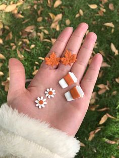 someone is holding out their hand with three small pieces of food on it, including marshmallows and an orange maple leaf