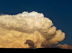 a large cloud is in the sky over a hill