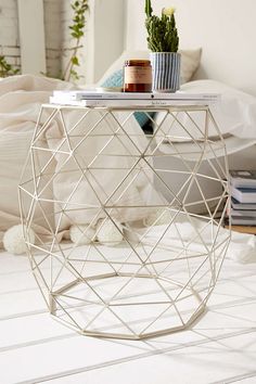 a white table sitting on top of a hard wood floor next to a bed in a room