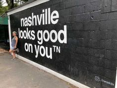 a man is standing in front of a wall that reads nashville books good on you