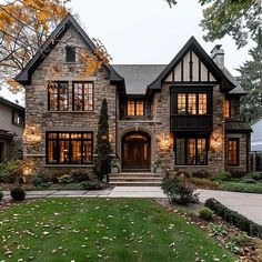 a large stone house with lots of windows and lights on it's front porch