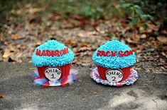 two red cupcakes with blue frosting sitting on the ground