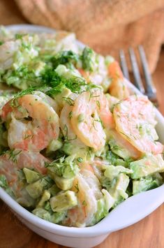 a bowl filled with shrimp and cucumber salad on top of a wooden table