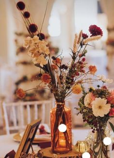 two vases filled with flowers sitting on top of a table