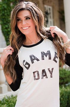 a beautiful young woman standing in front of a building wearing a white and black shirt